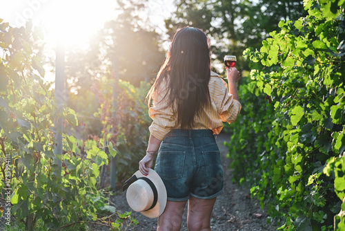 Young beautiful Smiling  italian woman walking at wineyard with a Glass of Red wine.Wine tourism at Tuscany,Italy