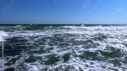 A storm at sea on a sunny day, white foam on the surface of the water