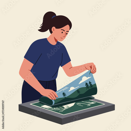 Woman carefully places a landscape print onto a screen printing frame