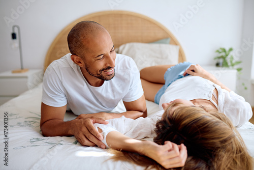 Принти на полотні Happy diverse couple relaxing in bedroom, sharing an intimate moment and enjoyin