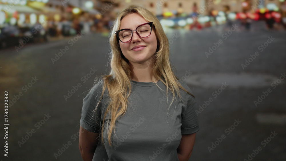Fototapeta premium Young woman smiling with closed eyes and hands on chest, standing on a lively city street outdoor in a casual setting, exuding happiness and confidence.