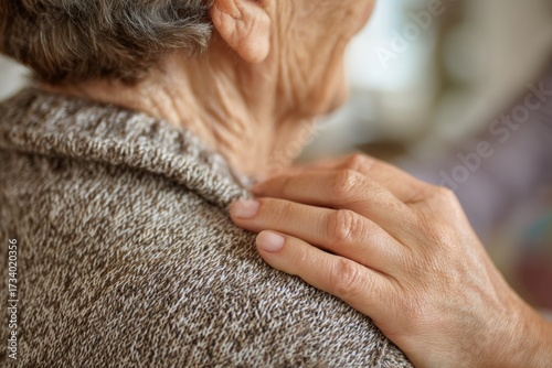 A caring hand gently rests on an elderly person's shoulder, conveying comfort, support, and empathy in a tender, intimate moment of human connection.
