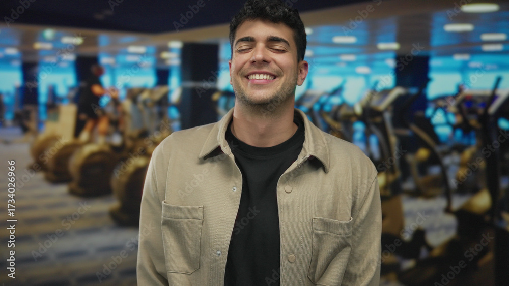 Naklejka premium Young hispanic man eyes closed smiling in gym; calm relief relaxation serenity.