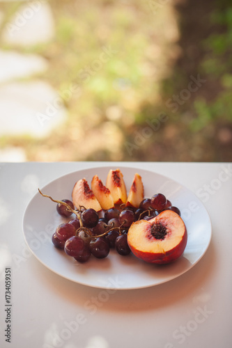 Peach and Grapes on White Plate with Floral Shadows, Sardinia, Horizontal Close Up with Copy Space