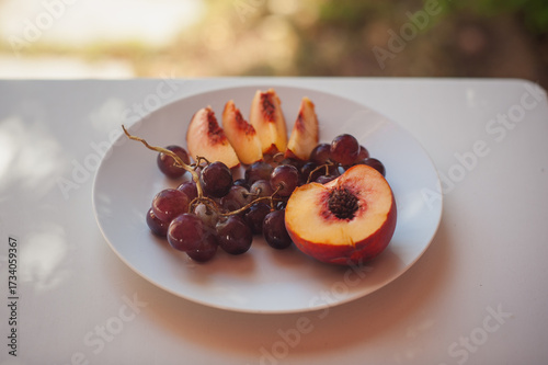 Peach and Grapes on White Plate with Floral Shadows, Sardinia, Horizontal Close Up with Copy Space