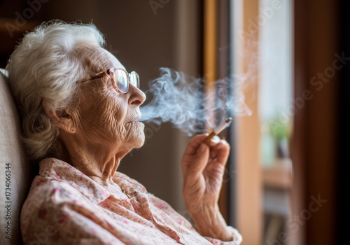 Profile portrait of old woman relaxing with cigarette at home