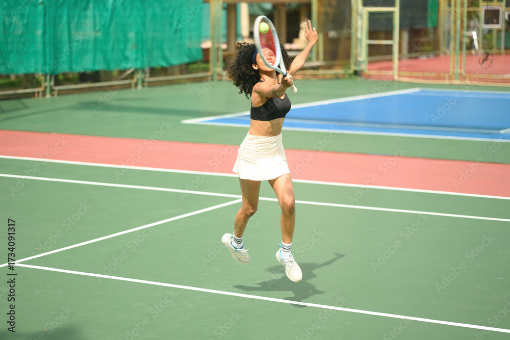 Obraz premium Energetic African sportswoman jumping to receive a tennis serve, practicing agility and precision on the court