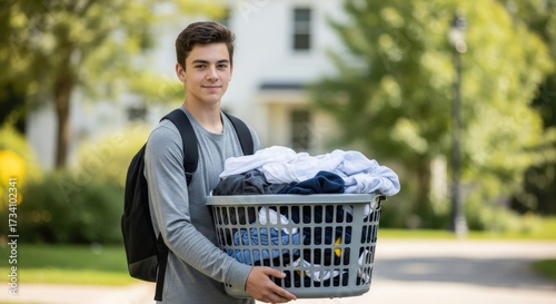 Young man carrying laundry basket with clean clothes, ready for dorm life or chores outdoors