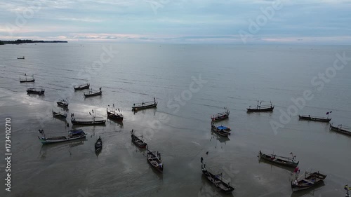 Aerial drone footage, many fishing boats on the murky and receding shore