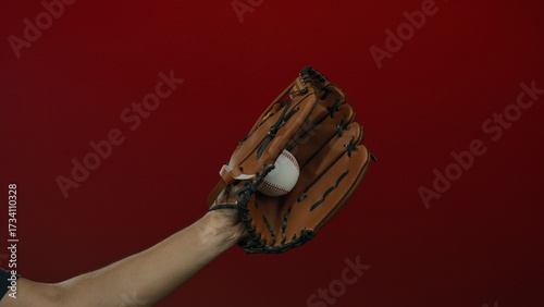 Photography Man catching baseball with glove against red background in a dynamic closeup showcasing sports action and athletic equipment for baseball enthusiasts