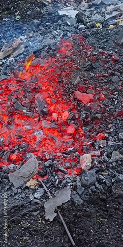 Glowing red embers and ash smolder in the dark — intense, raw, and primal, evoking heat, destruction, or the quiet power of fire after flames have faded.