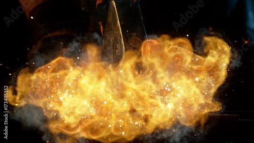 Close-up of blacksmith forging glowing hot iron on anvil with flying sparks. Super slow motion filmed on high-speed cinema camera at 1000 fps