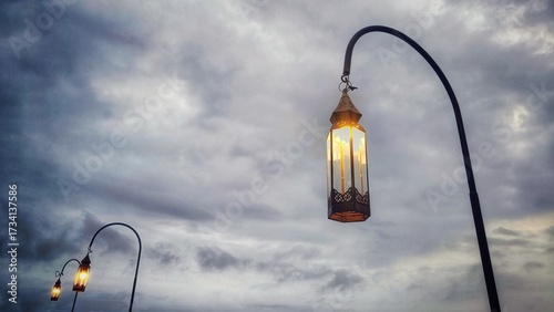 3 decorative garden lights lined up in a vintage style with an evening sky background.