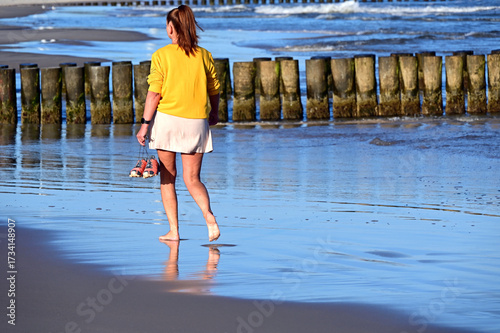 Ustka, Słupsk county, Pomorze, Pomerania, Poland, Europe : Ustka - popular holiday resort on South Coast of Baltic Sea, Slovincian Coast, young woman walking barefoot the beach in September