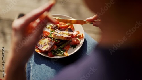 Woman eating salad with haloumi cheese and organic bio vegetables in sun