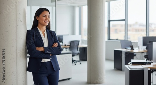  Portrait of confident female lawyer with arms crossed smiling and leaning on column in modern office 