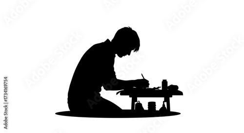 Focused student diligently studying and writing at a low table with study materials