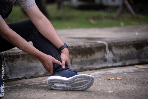 Close-up of runner holding painful ankle after exercise, concept of sports injury, sprain, or muscle strain during jogging or fitness training.