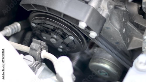 The alternator belt of the gasoline car's engine is turning with a natural sound at the moment of starting