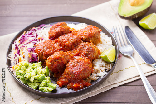 Colorful and appetizing plate of homemade meatballs served with with rice, avocado and creamy coleslaw