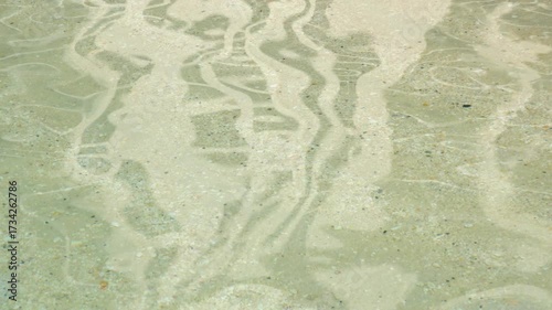 Gentle ripples dance across a clear water surface at the beach, capturing sunlight while creating an inviting and serene atmosphere in a coastal setting.