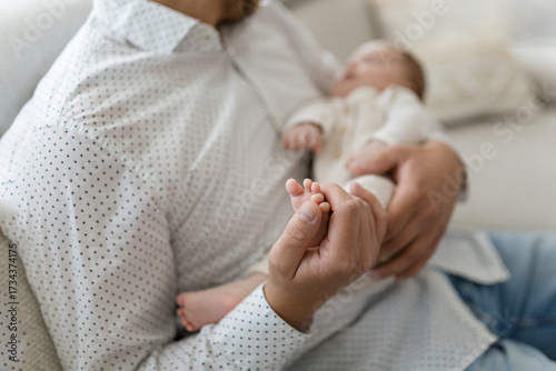 Füße eines winzigen Neugeborenen aus nächster Nähe. Kinderfuß in den Händen von Vater, Eltern. Kleine Babybeine. 