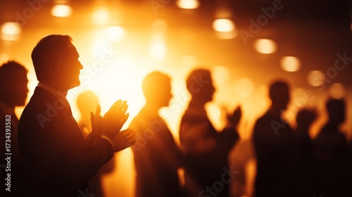 Silhouetted figures at a formal event with warm backlighting, audience members clapping, glowing ambiance,
