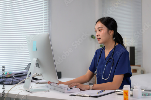 Female Asian doctor using computer in clinic office