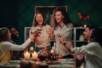 Friends toasting during thanksgiving dinner celebrating with wine and roasted turkey