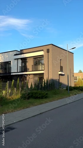 Curving street in lush greenery with designed Houses. Modern Residential Neighborhood on sunset. Road in closed residential community. Villa, stylish houses. Luxury houses in suburb. Designed homes. 