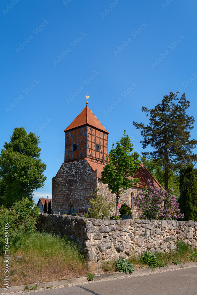 Fototapeta premium Eine massive Feldsteinmauer umgibt die denkmalgeschützte Dorfkirche 