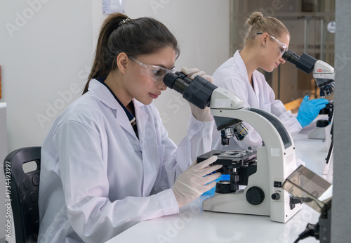Bild auf Leinwand Two scientists conduct research in a laboratory using microscopes during a brigh
