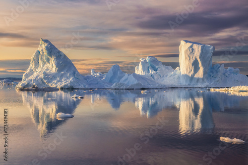 Pristine white iceberg in Greenland floating on calm waters, mirrored in the sea under a dreamy pastel sunset sky