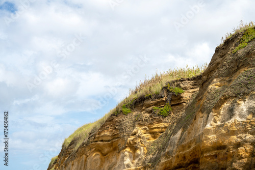 Coastal cliff of Santa Barbara Beach in the Azores with visible geological strata and vegetation growing on its slopes