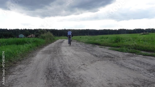 boy riding bicycle on rural dirt road in countryside