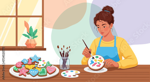 Artistic woman decorating cookies with colorful icing and paintbrushes in cozy kitchen setting