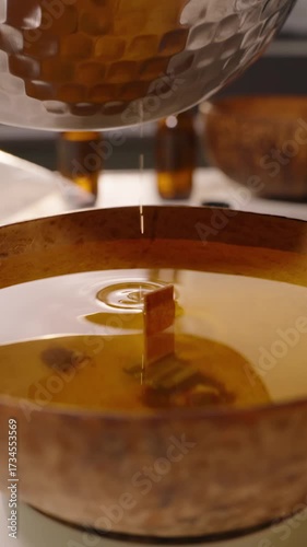 Vertical video. Stream of Melted Wax Flowing From Silver Pot Into Coconut Bowl With Wooden Wick Slow Motion, Candle Making Hobby Concept