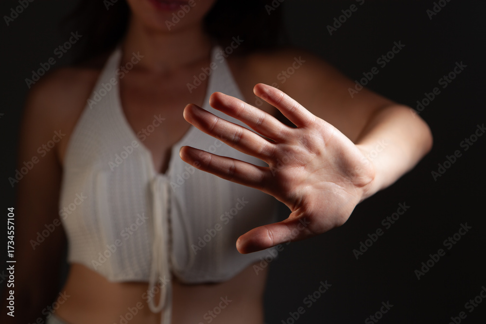 Fototapeta premium Woman in swimsuit showing stop gesture on dark background, closeup