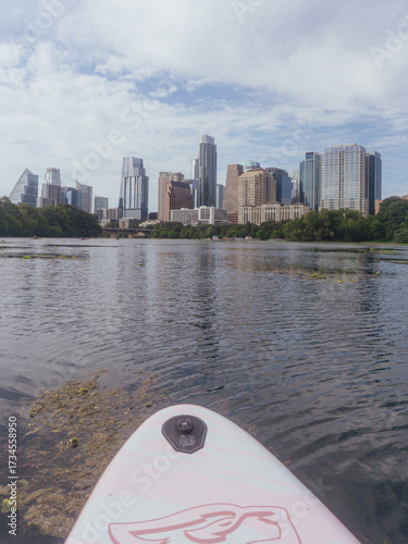 A scenic urban waterfront with tall modern buildings and calm reflective water under a clear sky. Perfect for depicting modern living and city tranquility.
