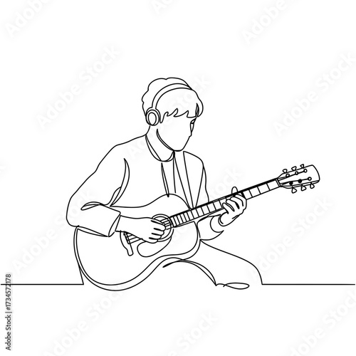 Young man playing acoustic guitar while listening to music  