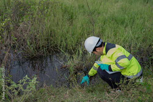 Foto Environmental engineer wearing safety gear collecting water sample from polluted pond for contamination analysis, environmental testing, and ecological impact assessment in natural outdoor setting