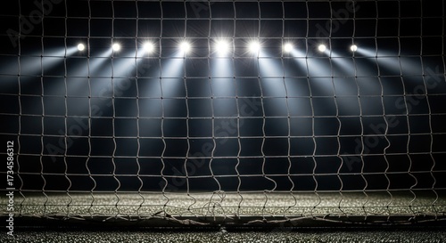 Soccer goal net with bright stadium lights shining in the dark background.