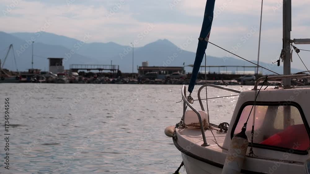 A boat is rocking gently on the calm sea in the marina. There are ...
