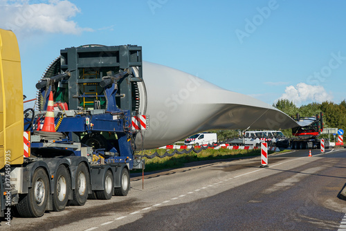 Fotografie Oversized transport of massive wind turbine blade on special truck for renewable