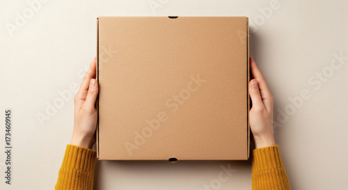 Hands holding blank cardboard pizza box for branding mockup on neutral background