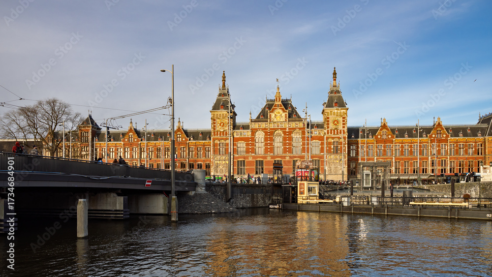 Obraz premium Amsterdam, Netherlands; February-24, 2025: View of the beautiful facade of Amsterdam Central Station (Netherlands) at sunset