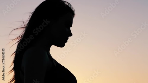 Silhouette of a woman against a vibrant sunset, capturing a moment of reflection and tranquility