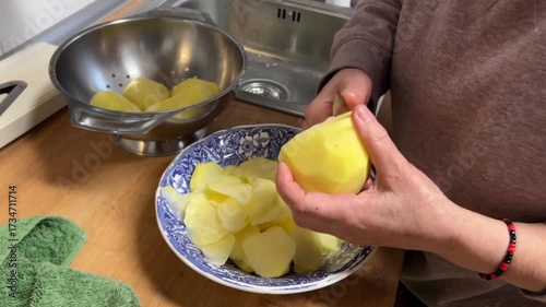 Close up of senior woman hands slicing potatoes in kitchen preparing traditional Spanish omelette