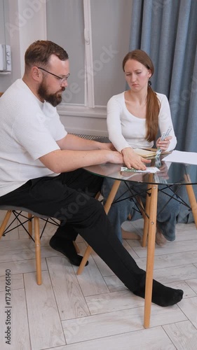 Young family carefully managing household finances, collaboratively counting euro banknotes and tracking expenses while sitting at kitchen table, focusing on budget planning and financial stability