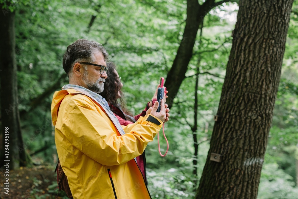 Fototapeta premium Father daughter hiking exploring forest with navigation device